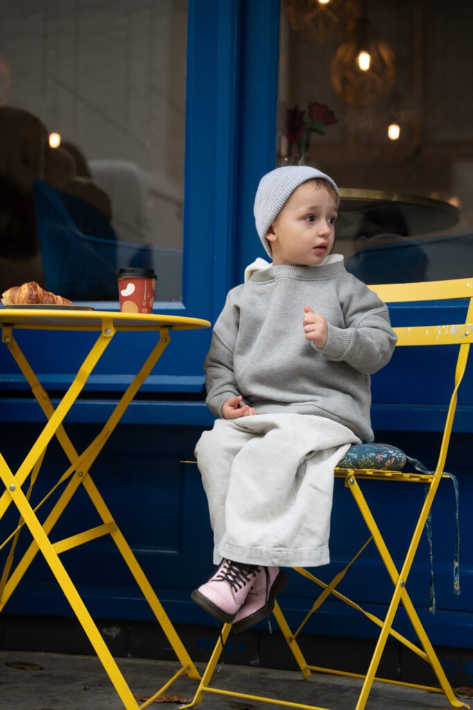 Toddler in the Tres London Soho hoodie sitting at a café table